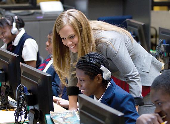 Teacher assisting students in a classroom with computers